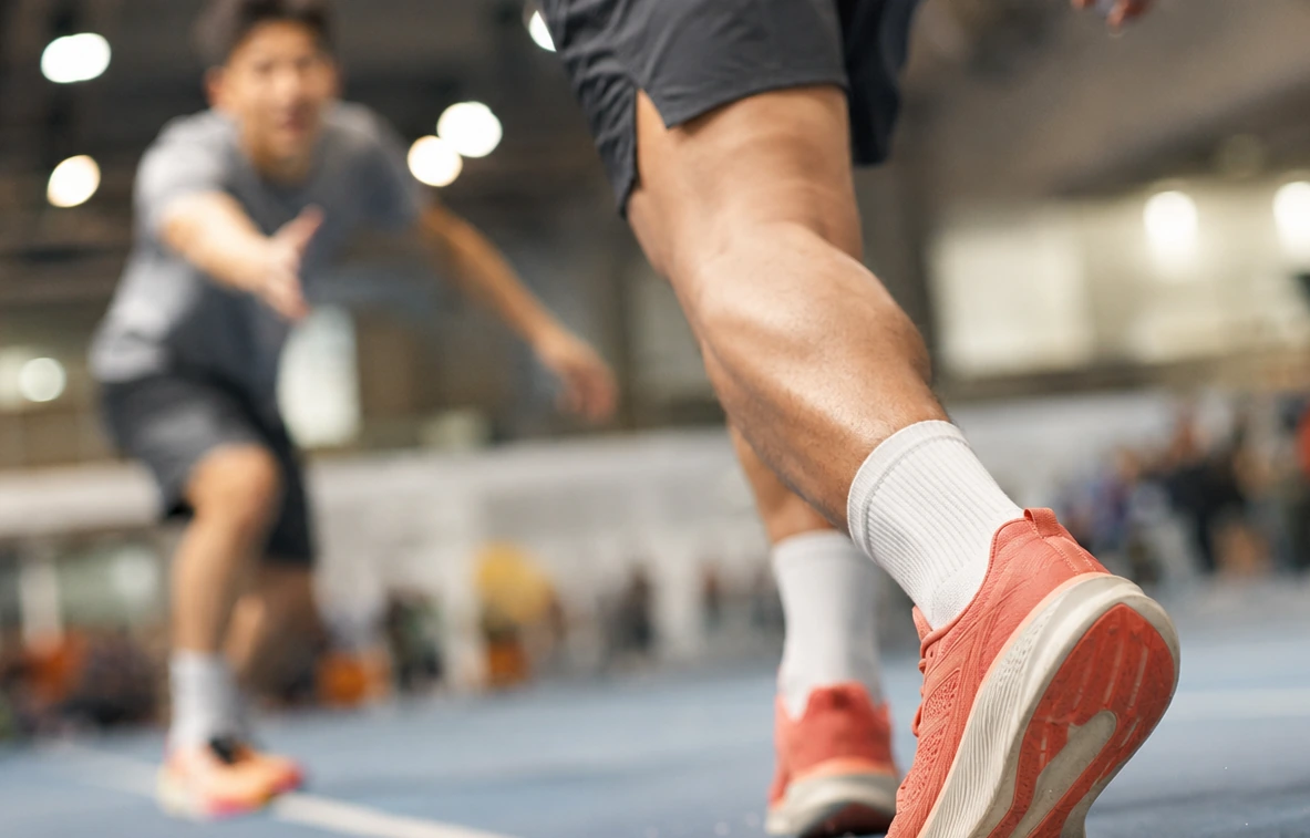 Two athletes running on an indoor sports court